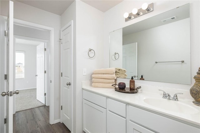 bathroom with vanity, wood finished floors, visible vents, and baseboards