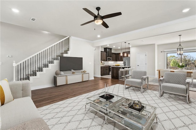 living room featuring crown molding, ceiling fan with notable chandelier, and light hardwood / wood-style flooring