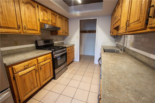 kitchen with gas range, sink, backsplash, a tray ceiling, and light tile patterned floors