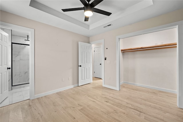 unfurnished bedroom featuring a raised ceiling, ceiling fan, and light hardwood / wood-style flooring