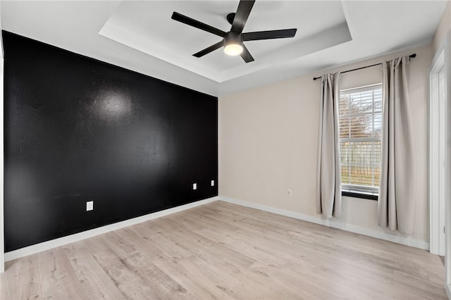 spare room featuring a tray ceiling, light hardwood / wood-style flooring, and ceiling fan