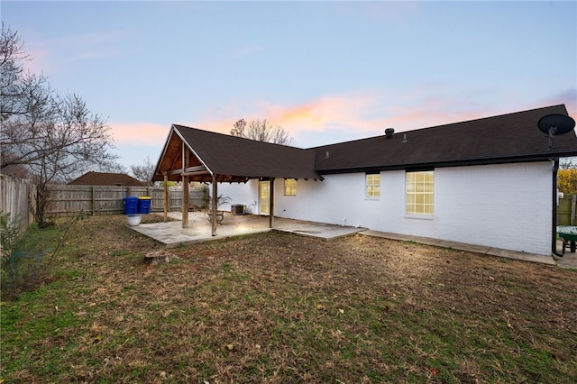 back house at dusk with a yard and a patio area