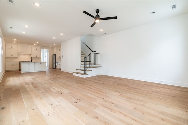 unfurnished living room with light wood-type flooring and ceiling fan