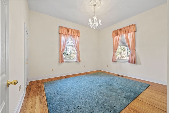 unfurnished room with a chandelier and wood-type flooring