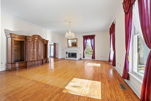 unfurnished living room with a chandelier, light hardwood / wood-style floors, crown molding, and a premium fireplace