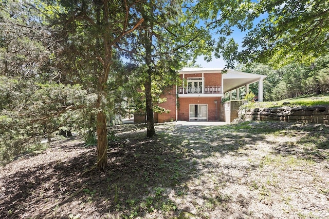 back of property with french doors, a patio, and a balcony