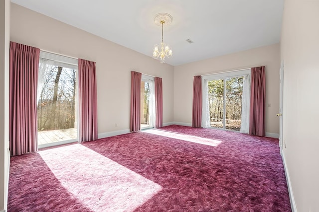 carpeted spare room featuring a healthy amount of sunlight and a notable chandelier