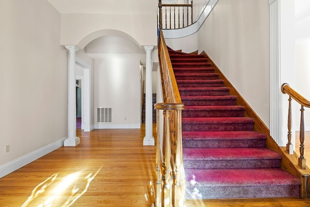 stairway with hardwood / wood-style flooring and decorative columns