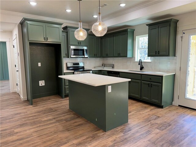 kitchen with sink, a center island, pendant lighting, wood-type flooring, and appliances with stainless steel finishes