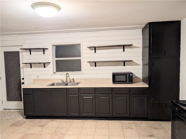 kitchen with black appliances, wood walls, crown molding, and sink