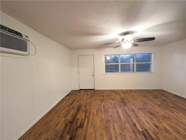 spare room featuring a textured ceiling, dark hardwood / wood-style floors, a wall unit AC, and ceiling fan