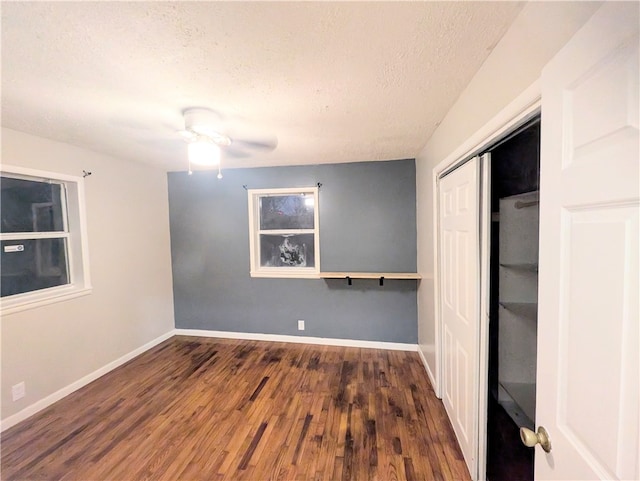 unfurnished bedroom with a textured ceiling, a closet, dark wood-type flooring, and ceiling fan