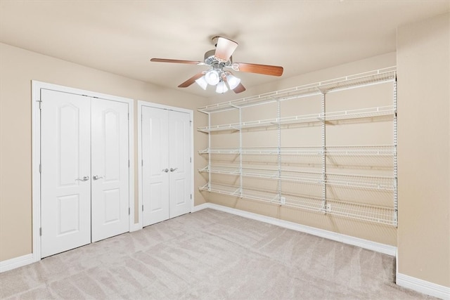 unfurnished bedroom with light carpet, two closets, and ceiling fan