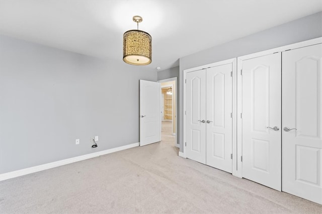 unfurnished bedroom featuring light carpet and two closets