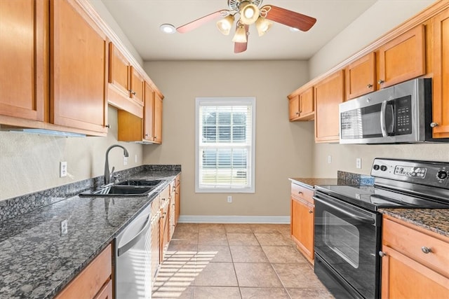 kitchen featuring light tile patterned floors, sink, appliances with stainless steel finishes, and dark stone counters