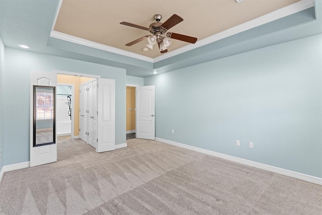 unfurnished bedroom featuring light carpet, a tray ceiling, and ceiling fan