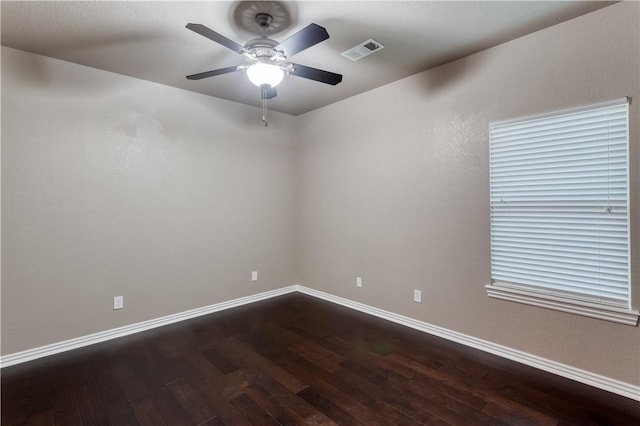 spare room featuring dark wood-type flooring, visible vents, baseboards, and a ceiling fan