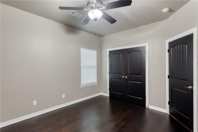 unfurnished bedroom featuring a ceiling fan, visible vents, dark wood finished floors, and baseboards