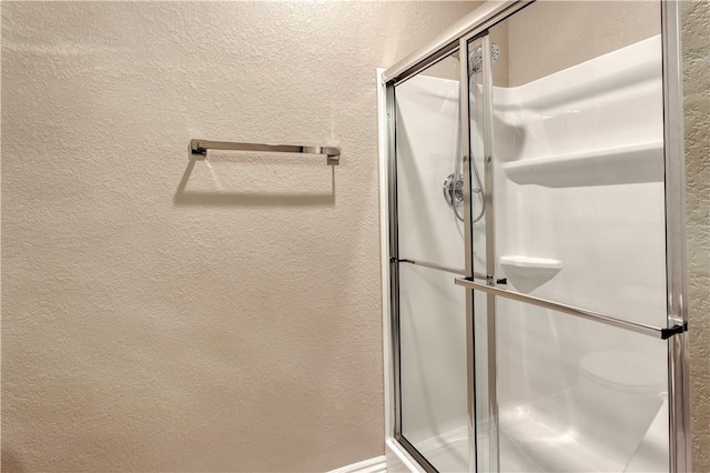 bathroom featuring a textured wall and a shower stall