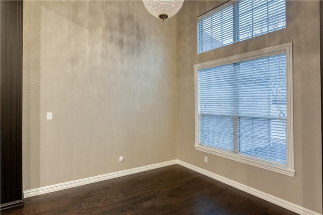 unfurnished room featuring baseboards and dark wood-type flooring