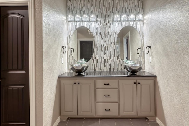 bathroom with a textured wall, a sink, and tile patterned floors