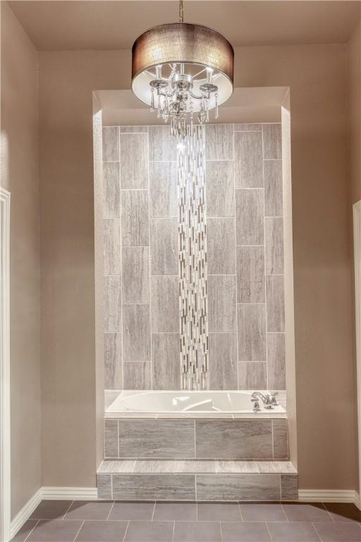 full bathroom with a chandelier, a relaxing tiled tub, baseboards, tile patterned floors, and walk in shower