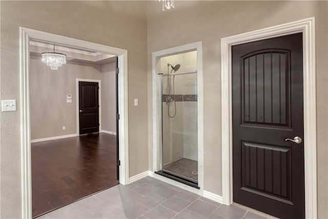 full bath featuring baseboards, an inviting chandelier, a shower stall, and tile patterned floors