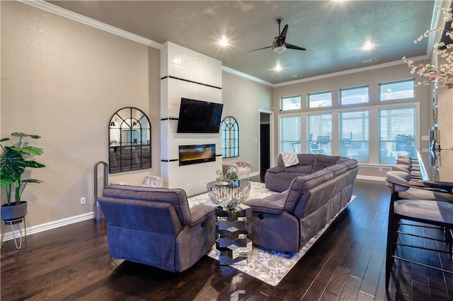 living area with a tiled fireplace, ornamental molding, ceiling fan, wood finished floors, and baseboards