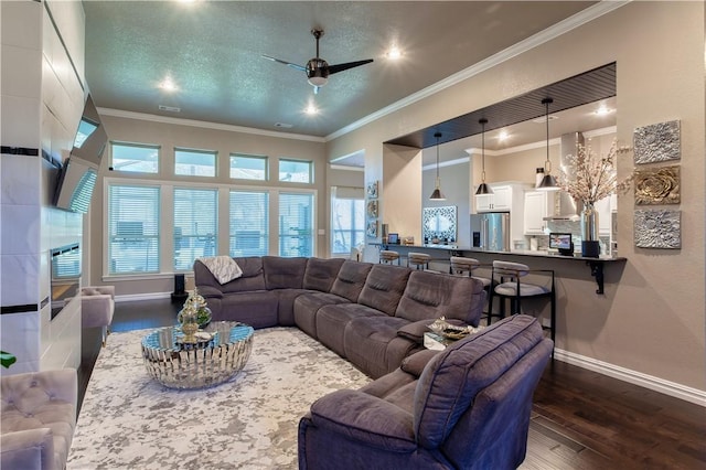 living room featuring baseboards, dark wood finished floors, ceiling fan, a textured ceiling, and crown molding