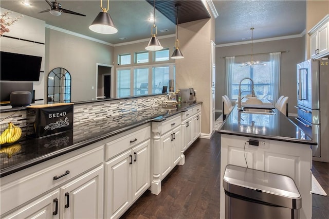 kitchen with dark wood-type flooring, a sink, white cabinetry, freestanding refrigerator, and decorative backsplash