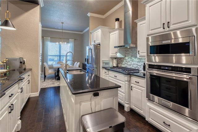 kitchen featuring dark wood finished floors, dark countertops, backsplash, appliances with stainless steel finishes, and wall chimney exhaust hood