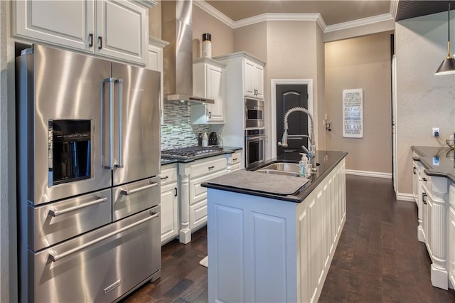 kitchen with appliances with stainless steel finishes, dark countertops, ornamental molding, and wall chimney range hood