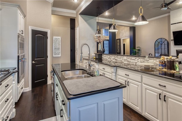 kitchen with dark wood-type flooring, dark countertops, a sink, and crown molding