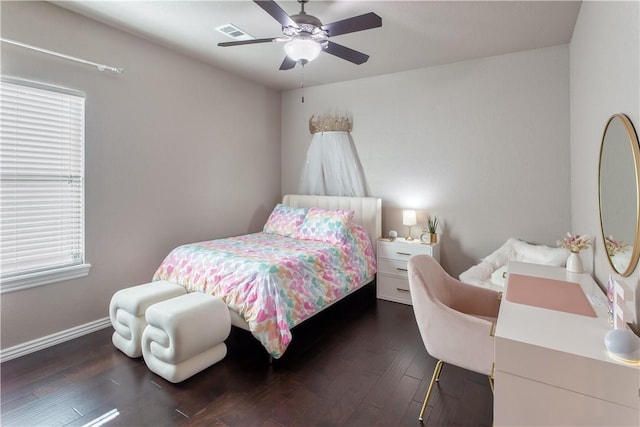 bedroom with a ceiling fan, visible vents, baseboards, and wood finished floors