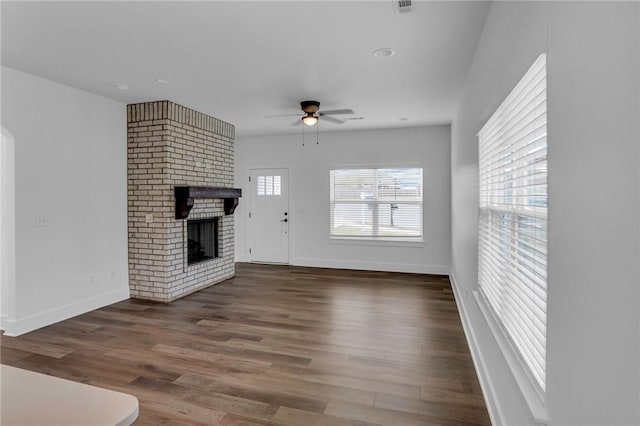 unfurnished living room featuring ceiling fan, dark hardwood / wood-style flooring, and a brick fireplace