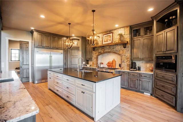 kitchen featuring sink, white cabinetry, decorative light fixtures, light wood-type flooring, and stainless steel appliances