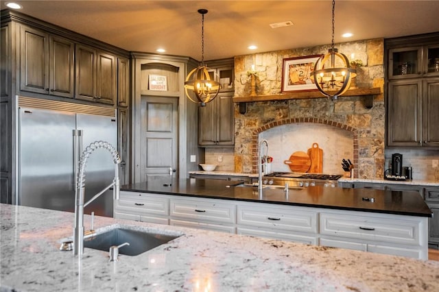 kitchen featuring sink, white cabinetry, hanging light fixtures, stainless steel built in fridge, and backsplash