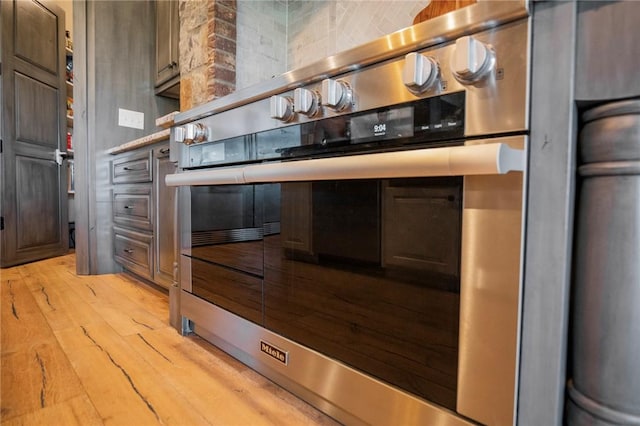 kitchen featuring tasteful backsplash, oven, dark brown cabinetry, and light hardwood / wood-style flooring