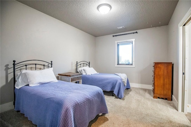 bedroom with light colored carpet and a textured ceiling