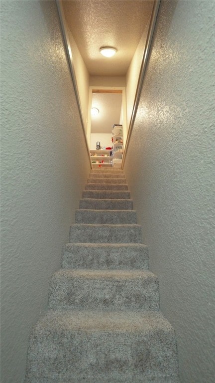 staircase featuring a textured ceiling