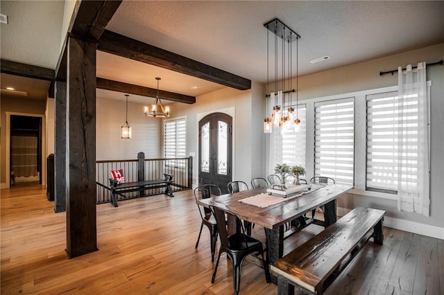 dining area featuring a notable chandelier, light hardwood / wood-style flooring, french doors, and beamed ceiling