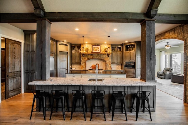 kitchen with a large island, hanging light fixtures, a kitchen breakfast bar, and light stone countertops