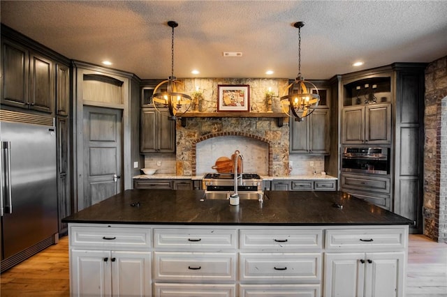 kitchen with decorative light fixtures, a center island with sink, white cabinets, and appliances with stainless steel finishes