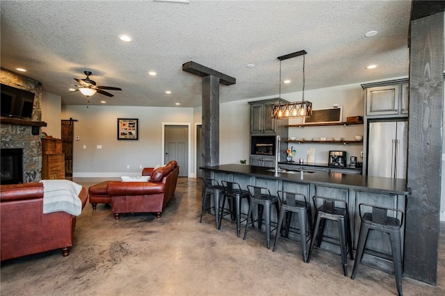 kitchen featuring pendant lighting, a kitchen breakfast bar, a textured ceiling, high end refrigerator, and concrete floors