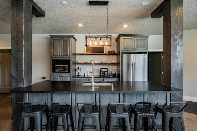 kitchen featuring sink, high end refrigerator, a breakfast bar, and a textured ceiling