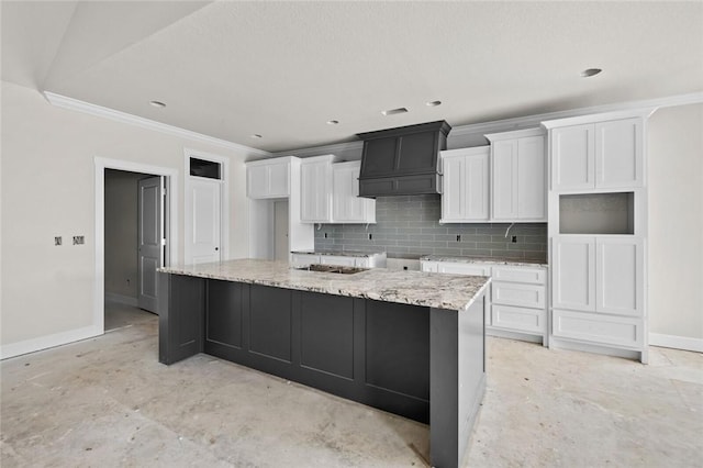 kitchen featuring white cabinets, tasteful backsplash, a large island, light stone counters, and custom range hood