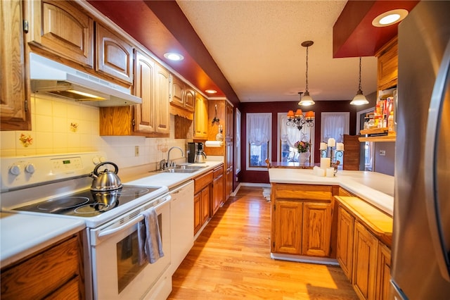 kitchen featuring sink, pendant lighting, white appliances, decorative backsplash, and light wood-type flooring