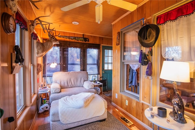 living area with wood walls, a healthy amount of sunlight, and hardwood / wood-style flooring