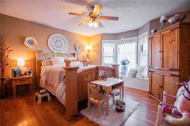 bedroom featuring ceiling fan, hardwood / wood-style floors, and a textured ceiling