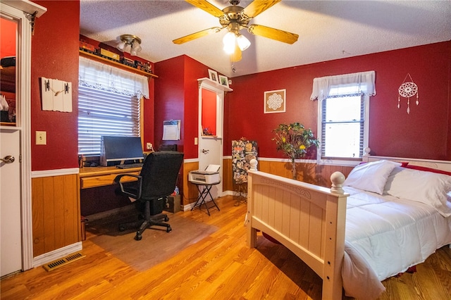 bedroom with a textured ceiling, light wood-type flooring, and ceiling fan